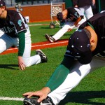 Baseball players warm up to improve hip flexibility.